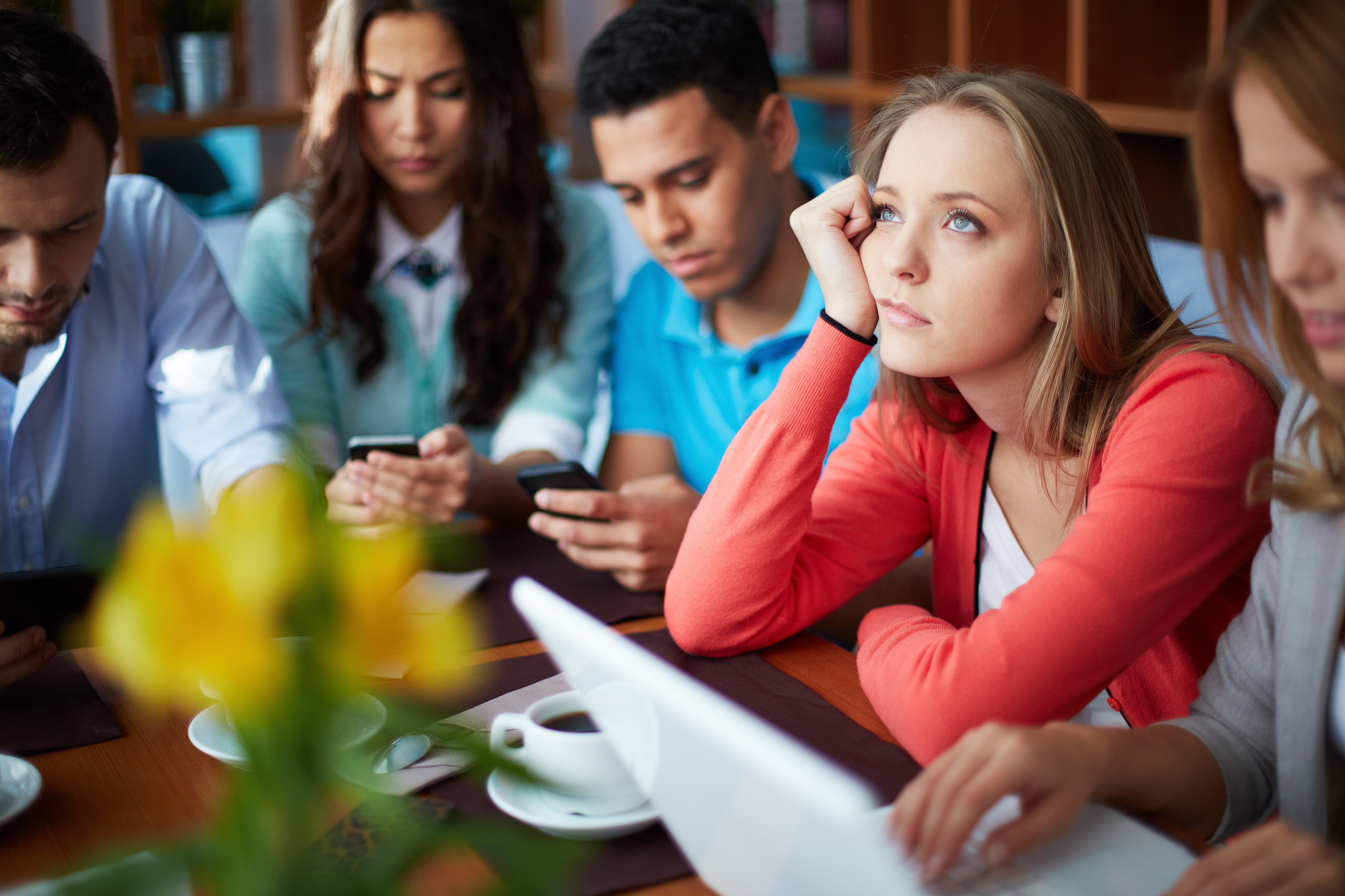 Portrait of teenage friends using modern gadgets while sitting in cafe, focus on pensive girl